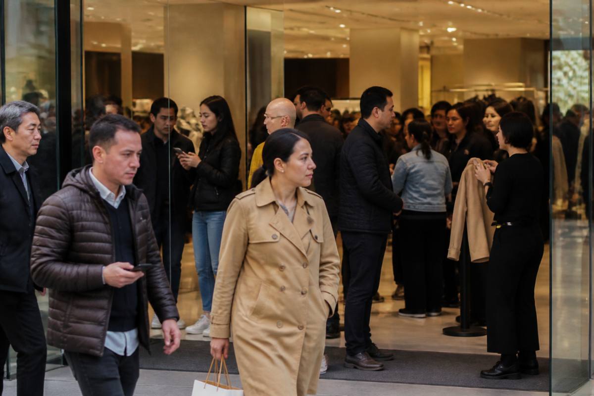 Trabalhadores e consumidores em movimento em um centro comercial movimentado.