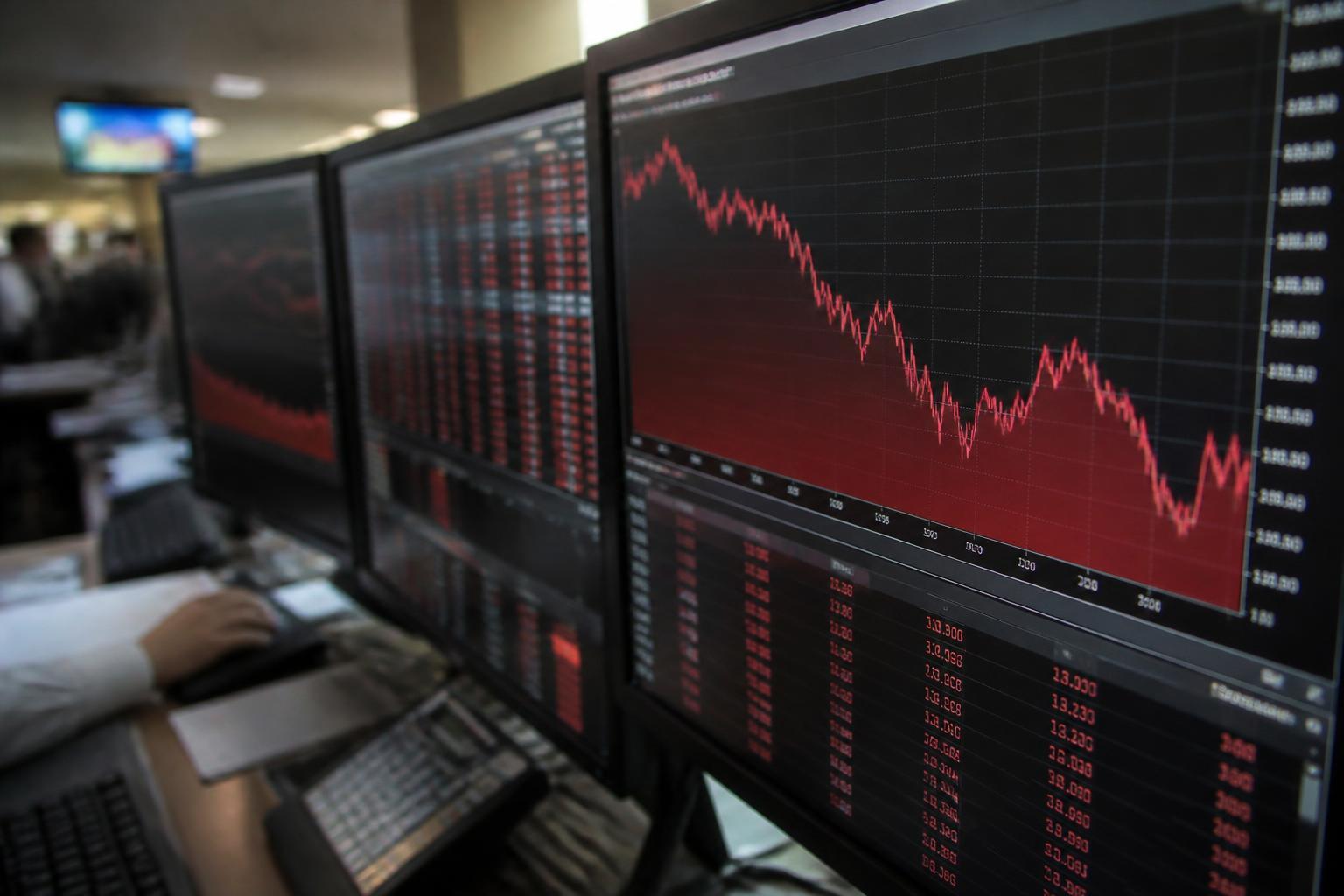 Monitores de mercado financeiro indicando queda em cotações de ações