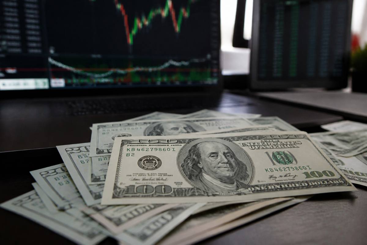 Notas de dólar sobre mesa com gráficos financeiros